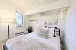 Experience cozy living in this charming bedroom featuring a unique angular window that floods the space with natural light.