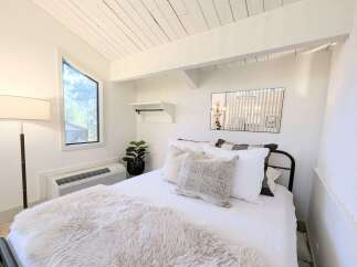 Experience cozy living in this charming bedroom featuring a unique angular window that floods the space with natural light.