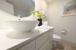 This modern bathroom features a sleek vanity with a white vessel sink and a chrome faucet, complemented by a large round mirror.