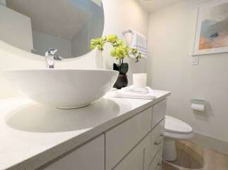 This modern bathroom features a sleek vanity with a white vessel sink and a chrome faucet, complemented by a large round mirror.