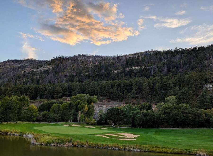 Experience the breathtaking beauty of this golf course nestled against a majestic mountain backdrop.