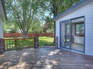 Enjoy outdoor living on this spacious wooden deck, perfect for entertaining or relaxing in the shade of mature trees.