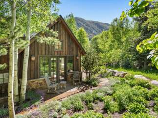 Nestled amidst lush greenery and mature trees, this charming rustic cabin offers a serene mountain retreat.