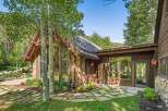 Experience rustic charm and modern luxury in this stunning mountain home, featuring a striking stone and wood exterior nestled amongst aspen trees.