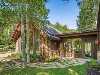 Experience rustic charm and modern luxury in this stunning mountain home, featuring a striking stone and wood exterior nestled amongst aspen trees.