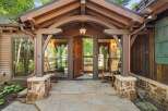 Step into this charming mountain retreat through a grand wooden door, flanked by inviting rocking chairs on a flagstone porch.