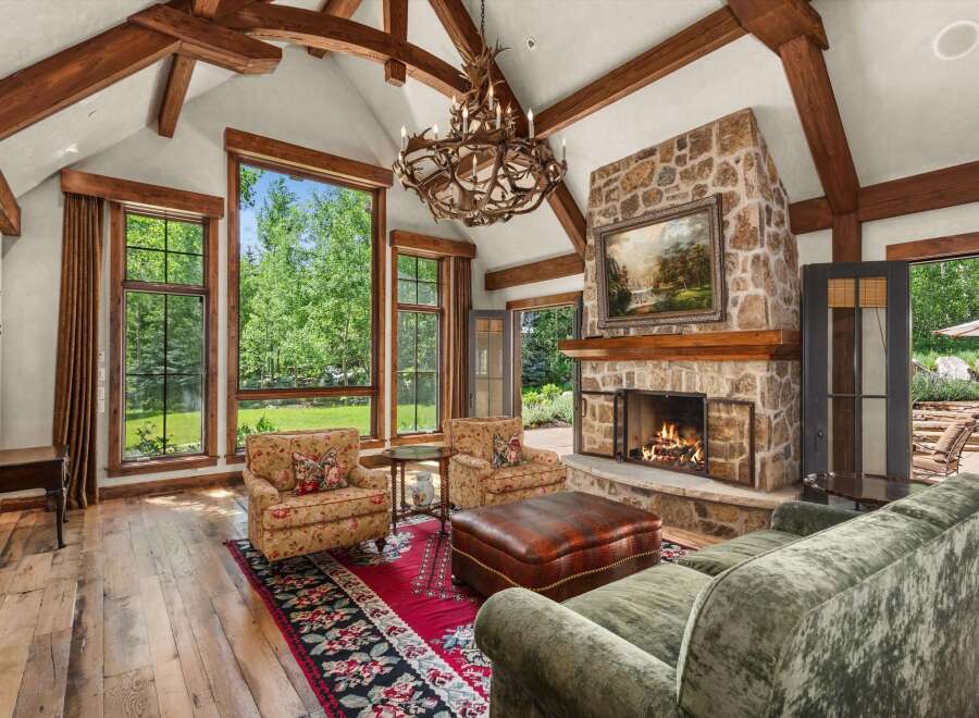 Experience rustic elegance in this stunning living room, featuring a grand stone fireplace and exposed wooden beams that add warmth and character.