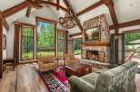 Experience rustic elegance in this stunning living room, featuring a grand stone fireplace and exposed wooden beams that add warmth and character.