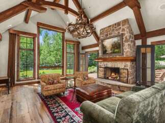 Experience rustic elegance in this stunning living room, featuring a grand stone fireplace and exposed wooden beams that add warmth and character.