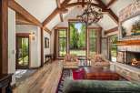Experience rustic luxury in this stunning living room, featuring soaring vaulted ceilings with exposed wooden beams and a grand stone fireplace.