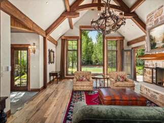 Experience rustic luxury in this stunning living room, featuring soaring vaulted ceilings with exposed wooden beams and a grand stone fireplace.