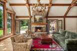 Experience rustic elegance in this stunning living room, featuring a grand stone fireplace and a unique antler chandelier.