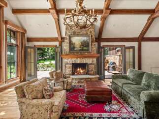 Experience rustic elegance in this stunning living room, featuring a grand stone fireplace and a unique antler chandelier.