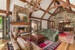 Experience rustic luxury in this stunning living room featuring a grand stone fireplace and exposed wooden beams.