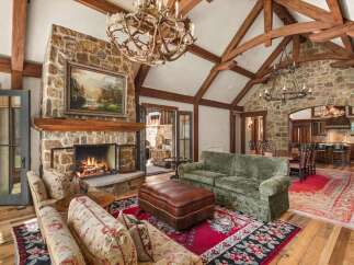Experience rustic luxury in this stunning living room featuring a grand stone fireplace and exposed wooden beams.