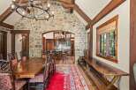 Experience rustic elegance in this stunning dining room, featuring a grand stone accent wall and exposed wooden beams that create a warm, inviting atmosphere.