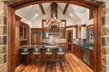 Experience rustic luxury in this stunning mountain kitchen, featuring a grand antler chandelier and a vaulted ceiling with exposed wooden beams.