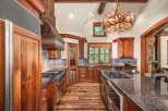Experience rustic luxury in this stunning mountain kitchen, featuring custom wood cabinetry and a grand antler chandelier.