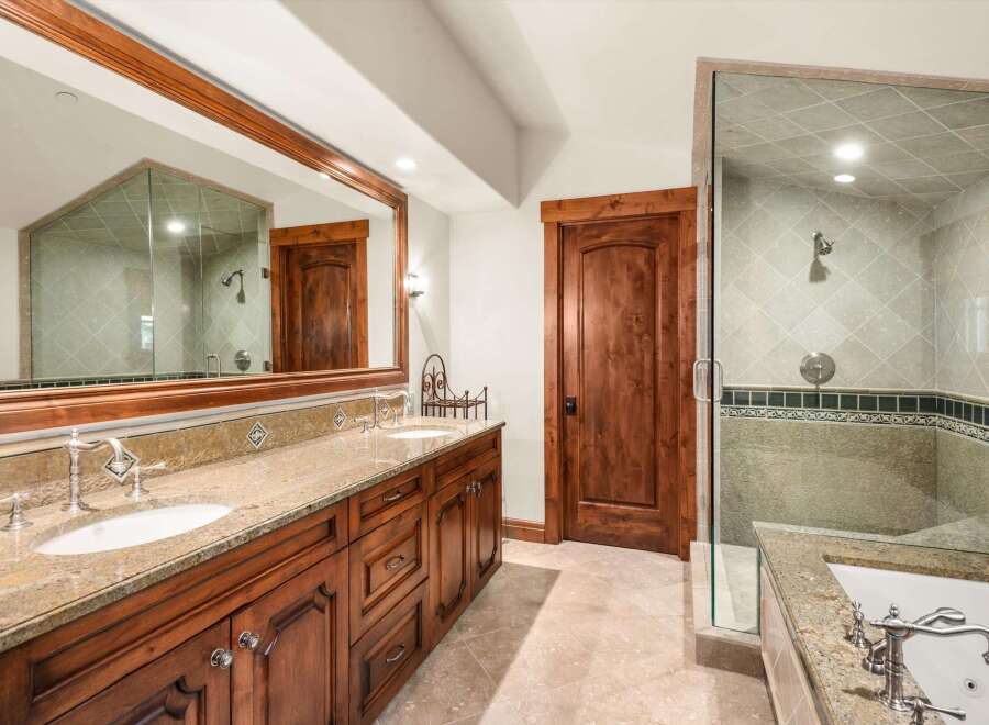 Experience luxury in this stunning bathroom featuring a spacious double vanity with granite countertops and elegant wooden cabinetry.