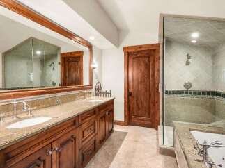 Experience luxury in this stunning bathroom featuring a spacious double vanity with granite countertops and elegant wooden cabinetry.