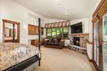 Experience rustic luxury in this spacious bedroom featuring a grand four-poster bed and a cozy stone fireplace.