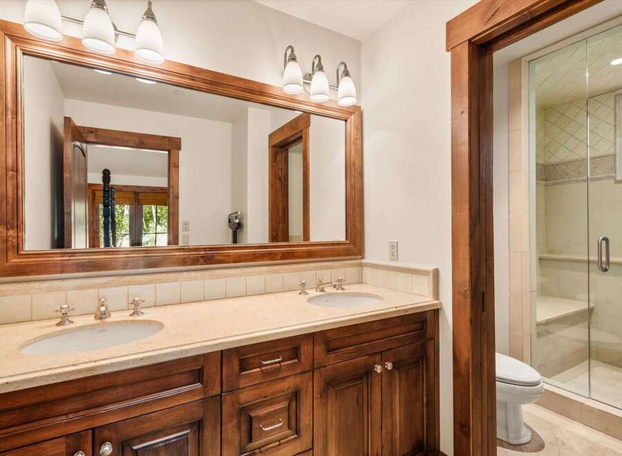 This luxurious bathroom features a double vanity with a large wooden framed mirror and ample counter space.