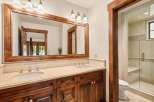 This luxurious bathroom features a double vanity with a large wooden framed mirror and ample counter space.