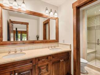 This luxurious bathroom features a double vanity with a large wooden framed mirror and ample counter space.