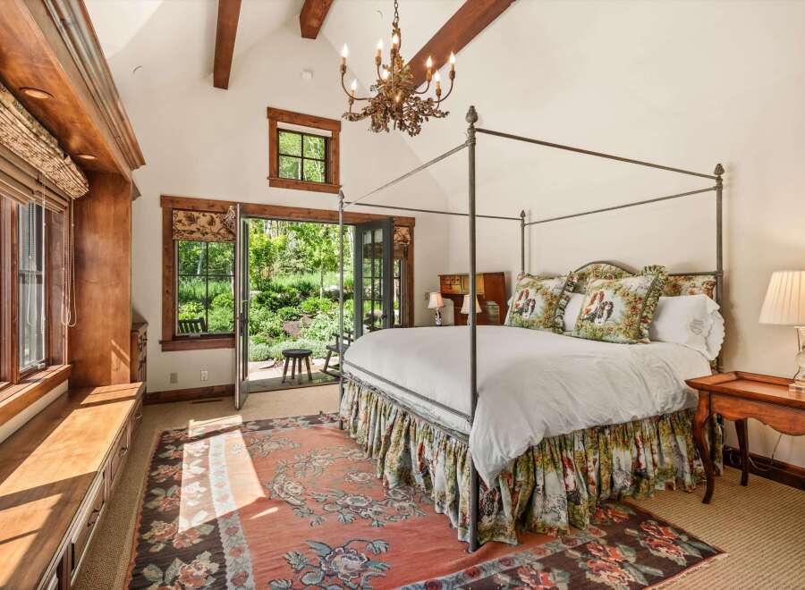Experience rustic elegance in this charming bedroom, featuring a grand four-poster bed adorned with decorative pillows and a scenic bed skirt.