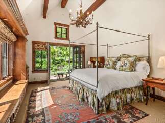 Experience rustic elegance in this charming bedroom, featuring a grand four-poster bed adorned with decorative pillows and a scenic bed skirt.
