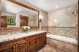 This luxurious bathroom features a spacious double vanity with a wooden cabinet and a stone countertop, complemented by elegant chrome fixtures.