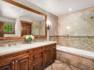 This luxurious bathroom features a spacious double vanity with a wooden cabinet and a stone countertop, complemented by elegant chrome fixtures.