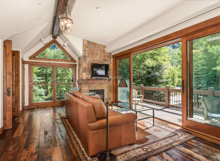 Experience rustic luxury in this stunning living room, featuring a natural stone fireplace and a large leather sofa perfect for cozy evenings.