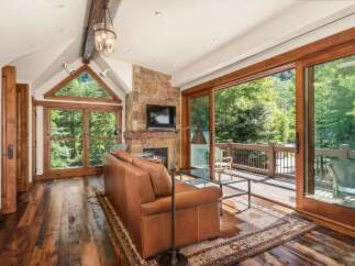 Experience rustic luxury in this stunning living room, featuring a natural stone fireplace and a large leather sofa perfect for cozy evenings.