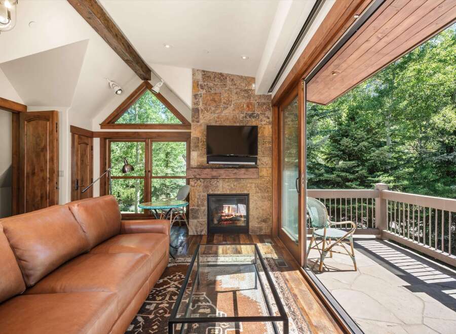 Experience luxurious living in this stunning mountain retreat, featuring a cozy stone fireplace and a spacious leather sofa perfect for relaxing.