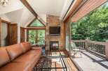 Experience luxurious living in this stunning mountain retreat, featuring a cozy stone fireplace and a spacious leather sofa perfect for relaxing.