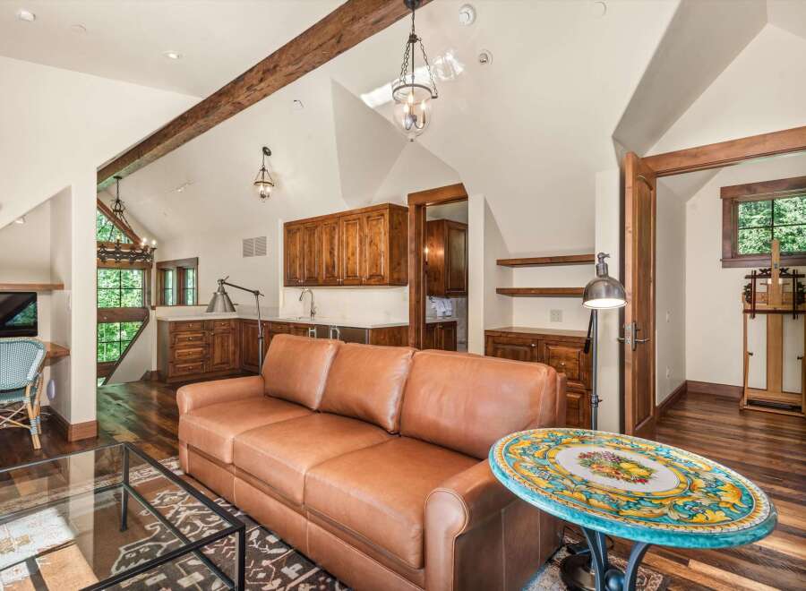 Experience rustic charm in this spacious living area featuring exposed wooden beams and a vaulted ceiling.