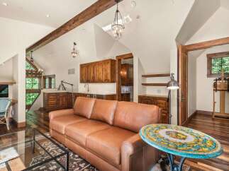 Experience rustic charm in this spacious living area featuring exposed wooden beams and a vaulted ceiling.