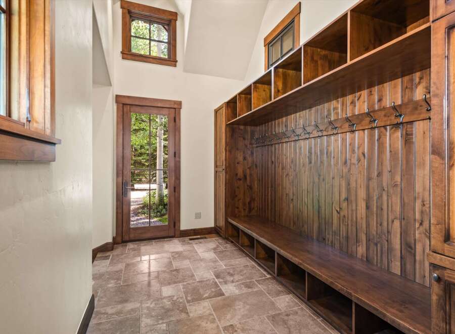 Step into this charming mudroom featuring a rustic wooden bench with ample storage cubbies and a wall of hooks for coats and accessories.