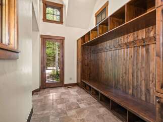 Step into this charming mudroom featuring a rustic wooden bench with ample storage cubbies and a wall of hooks for coats and accessories.