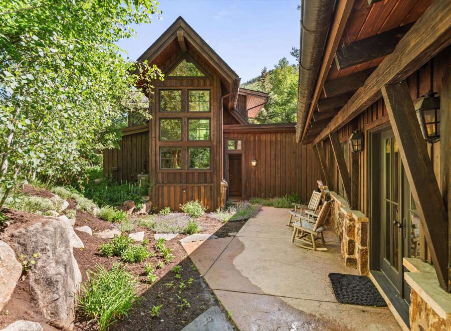Experience rustic charm in this mountain retreat, featuring a stunning multi-story wood-paneled facade with expansive windows that capture the natural surroundings.