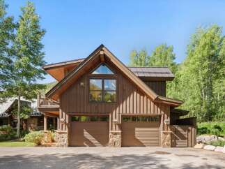This stunning mountain home features a rustic wood exterior complemented by stone accents and a durable metal roof.
