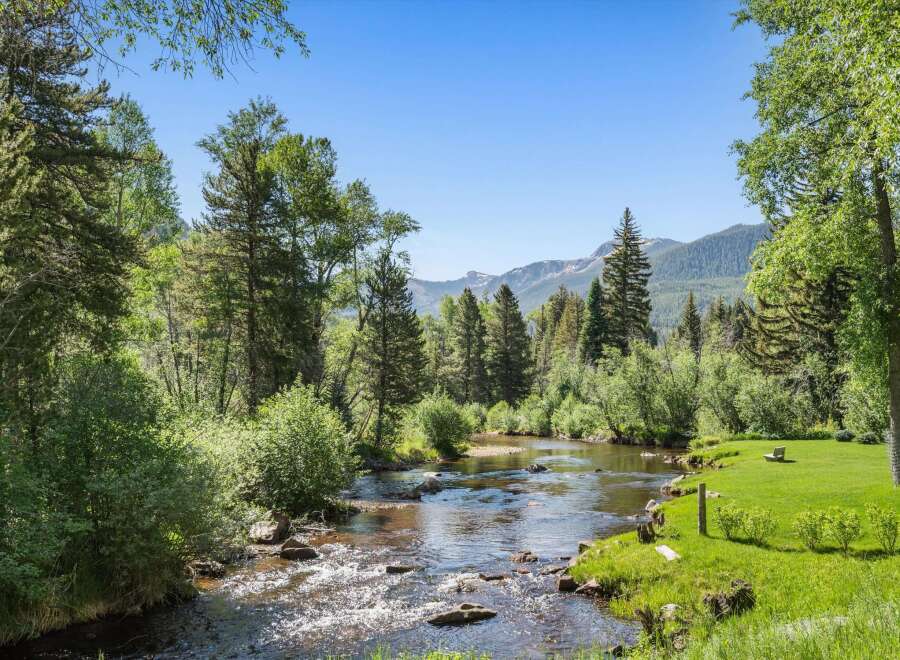 Experience serene living with this stunning property featuring a tranquil river flowing through lush greenery.
