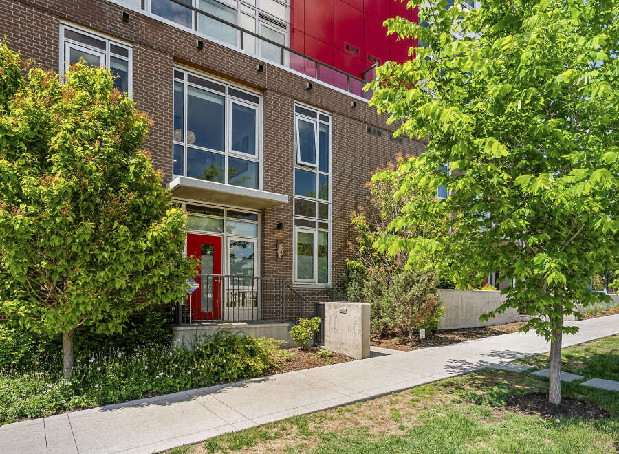 Discover modern urban living in this stunning brick townhouse featuring a vibrant red front door and expansive windows that flood the interior with natural light.