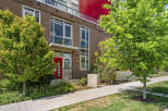 Discover modern urban living in this stunning brick townhouse featuring a vibrant red front door and expansive windows that flood the interior with natural light.
