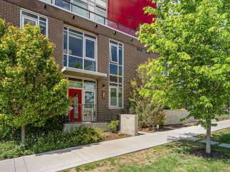 Discover modern urban living in this stunning brick townhouse featuring a vibrant red front door and expansive windows that flood the interior with natural light.
