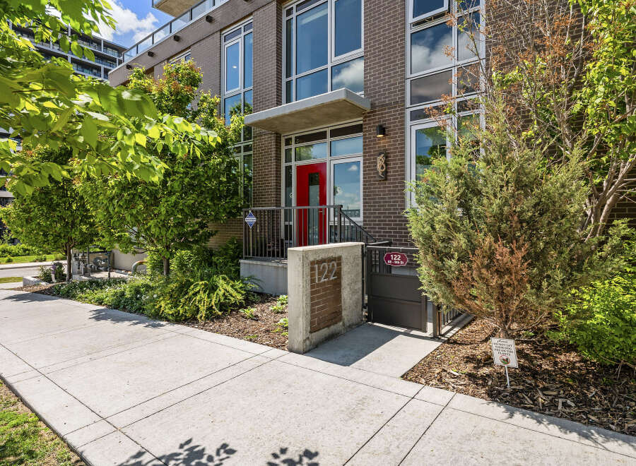 Discover modern urban living in this stunning brick building, featuring a vibrant red front door and large windows that invite natural light.