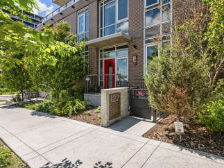 Discover modern urban living in this stunning brick building, featuring a vibrant red front door and large windows that invite natural light.