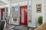 Welcome guests into this stylish entryway featuring a vibrant red door and ample natural light from the surrounding windows.