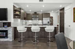 Experience modern living in this stunning kitchen featuring sleek dark wood cabinetry and a spacious quartz countertop island.